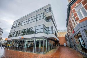 a large glass building on a city street at Alphabet Studio Apartments including City view in Hilversum