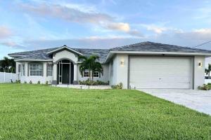 a large white house with a garage at Tranquil & Inviting! 4BR, 2.5BA heated pool home! in Cape Coral