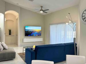 a living room with a blue couch and a tv at Tranquil & Inviting! 4BR, 2.5BA heated pool home! in Cape Coral