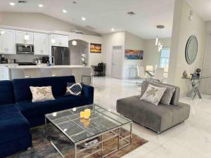 a living room with a blue couch and a glass table at Tranquil & Inviting! 4BR, 2.5BA heated pool home! in Cape Coral