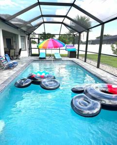 a swimming pool with an umbrella and tires in the water at Tranquil & Inviting! 4BR, 2.5BA heated pool home! in Cape Coral