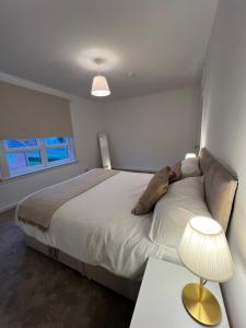 a bedroom with a bed and a table with a lamp at Archillects - Entire Two Bedroom Comfy House in Glasgow