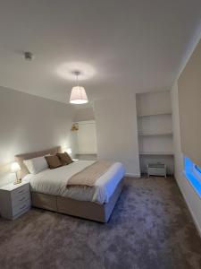 ein Schlafzimmer mit einem großen Bett und einer Lampe in der Unterkunft Archillects - Entire Two Bedroom Comfy House in Glasgow