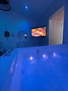 Cette chambre dispose d'une télévision et d'une grande baignoire bleue. dans l'établissement SPA JUNGLE, à Le Mesnil-Saint-Denis
