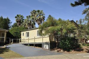 una casa amarilla con palmeras y entrada en Big4 Sydney Lakeside Holiday Park, en Narrabeen