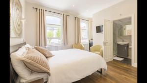 a bedroom with a white bed and a bathroom at Alexander House in London