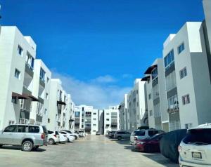 Bello y comodo apartment , residencial con piscina, seguridad las 24 Horas في Licey al Medio: صف من السيارات المركونه في موقف للسيارات