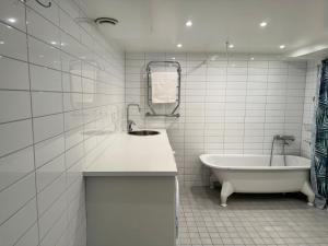 a white bathroom with a tub and a sink at Apartment with amazing view in Stockholm