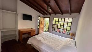 a bedroom with a bed and a desk and windows at Campus Residencias in Quito