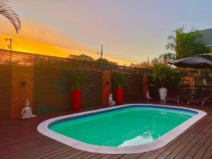 a swimming pool on a deck with a sunset in the background at Pousada Rosa Karioka in Praia do Rosa