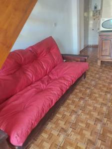 um sofá de couro vermelho sentado num piso de madeira em Cabañas Los Materos em Santa María