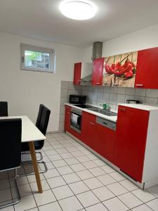La cuisine est équipée de placards rouges, d'une table et d'un évier. dans l'établissement Gartenparadies mit Rheinblick in Urbar, à Urbar