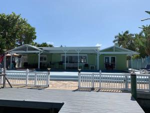 a green house with a white fence in front of it at Oceanview home on Indian Rocks Beach in Clearwater Beach