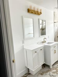 Baño blanco con lavabo y espejo en Joys Galleria Luxury Homes, en Houston