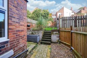 un jardín con una pared de ladrillo y escaleras junto a una valla en Hamilton House en Sheffield