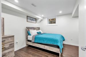 a bedroom with white walls and a bed with blue sheets at Modern 1 Bedroom + Den in Cambridge in Cambridge