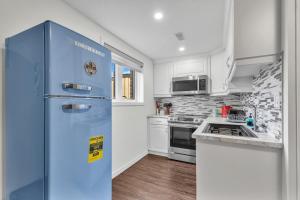 a blue refrigerator in a kitchen with white cabinets at Modern 1 Bedroom + Den in Cambridge in Cambridge