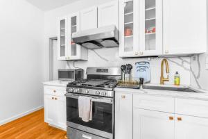 a white kitchen with a stove and white cabinets at Welcome to “Sunny Park Slope Retreat”! in Brooklyn