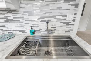 a stainless steel sink in a kitchen with a tile wall at Modern 1 Bedroom + Den in Cambridge in Cambridge