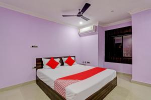 Un dormitorio con una cama con almohadas rojas y una ventana en Flagship VENTURE INN GUEST HOUSE en Bhubaneshwar