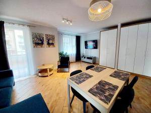 a living room with a table and chairs in a room at Kolory Warmii Apartament Niebieski in Olsztyn