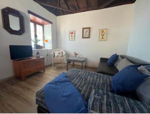 een slaapkamer met een bed en een tv en een bank bij Finca La Calzada in Los Quemados