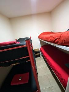 Hostel El Paredon في إل تشالتين: سريرين بطابقين في غرفة مع ملاءات حمراء