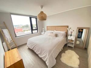a bedroom with a white bed and a window at Acogedor departamento in Puerto Varas