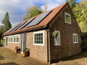 a small brick house with solar panels on it at The Old Workshop, Wadhurst in Wadhurst
