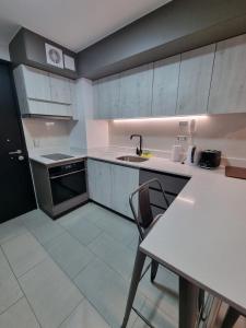 a kitchen with white cabinets and a table and a sink at Apartamentos Bauerle Curitiba in Temuco