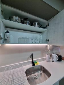 a kitchen counter with a sink and some pots and pans at Apartamentos A&B Curitiba in Temuco