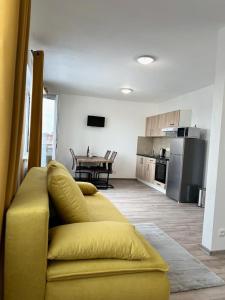 a living room with a yellow couch and a kitchen at Sky Apartments 511 in Plzeň