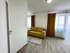 a living room with a yellow couch and windows at Sky Apartments 511 in Plzeň