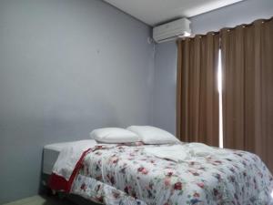 a bedroom with a bed with a blanket and a window at Hotel Caçula São Gabriel in São Gabriel