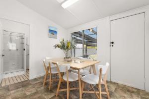 a dining room with a wooden table and chairs at The Gunyah by Experience Jervis Bay in Huskisson +14 photos