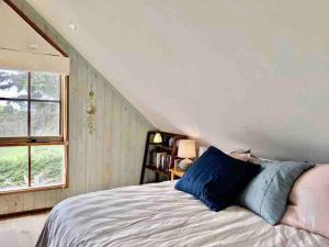 a bedroom with a bed with blue pillows and a window at Alyeska Loft - Apollo Bay studio loft apartment in Apollo Bay