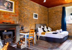 a room with a bed and a table and a fireplace at Reillys Wines Heritage Cottages in Mintaro