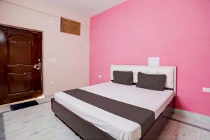 a bedroom with a large bed with a pink wall at OYO Home Tilak Hotel 24 in Noida