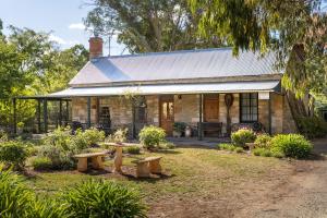 a stone house with benches in front of it at Reillys Wines Heritage Cottages in Mintaro