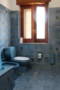 W wyłożonej niebieskimi kafelkami łazience znajduje się toaleta i umywalka. w obiekcie Camera a Grammichele w mieście Grammichele