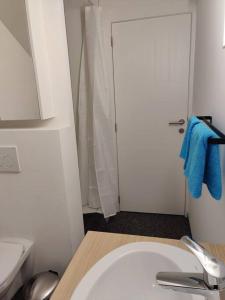 bagno con lavandino bianco e asciugamano blu di Corso studio 0303 a Lovanio