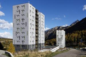 a tall white apartment building next to another building at Apartment Tonale in Passo del Tonale