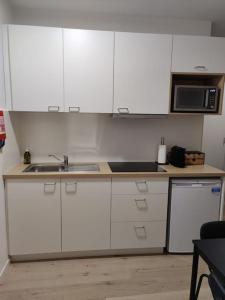 uma cozinha com armários brancos, um lavatório e um micro-ondas em Corso studio 0303 em Lovaina
