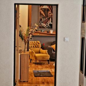a living room with a yellow chair and a couch at Apartman Kalina in Novi Sad