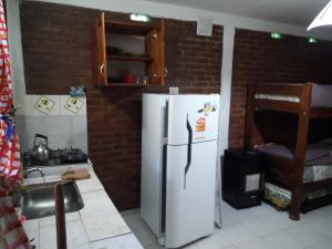 cocina con nevera blanca y pared de ladrillo en Departamentos Don Carlos en Villa Cura Brochero