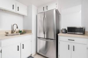- un réfrigérateur en acier inoxydable dans une cuisine avec des placards blancs dans l'établissement Modern Loft in Mission / Hayes Valley with Parking, à San Francisco