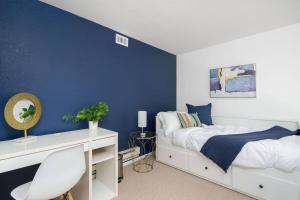 um quarto com paredes azuis, uma cama branca e uma secretária em Modern Loft in Mission / Hayes Valley with Parking em São Francisco