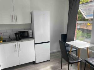 a kitchen with white cabinets and a table and a microwave at Studio Flat Private Shower Wc and Kitchenette in London