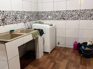 a kitchen with a sink and a washing machine at Acomodação Três Fronteiras Foz in Foz do Iguaçu
