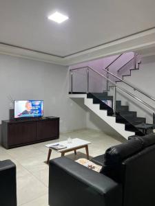 a living room with a staircase and a tv at Acomodação Três Fronteiras Foz in Foz do Iguaçu